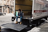man in blue denim jeans sitting on black and white trailer