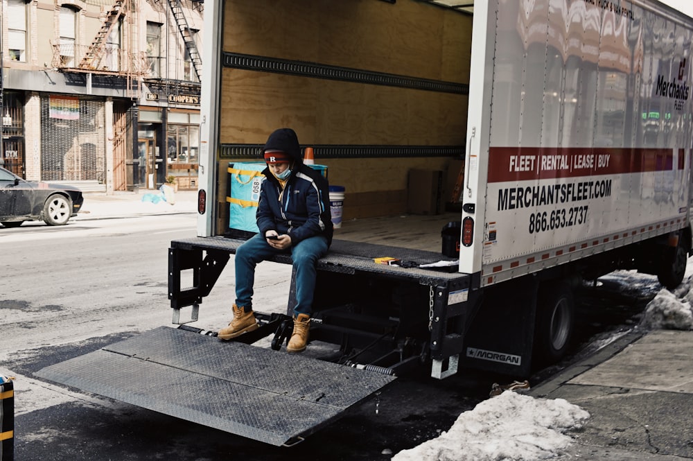 man in blue denim jeans sitting on black and white trailer