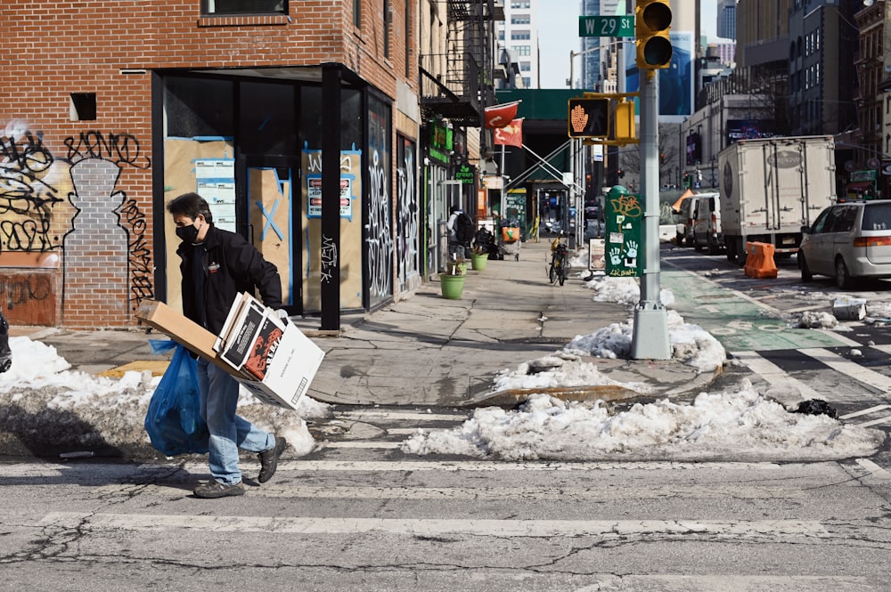 man in black jacket and blue denim jeans sitting on sidewalk during daytime