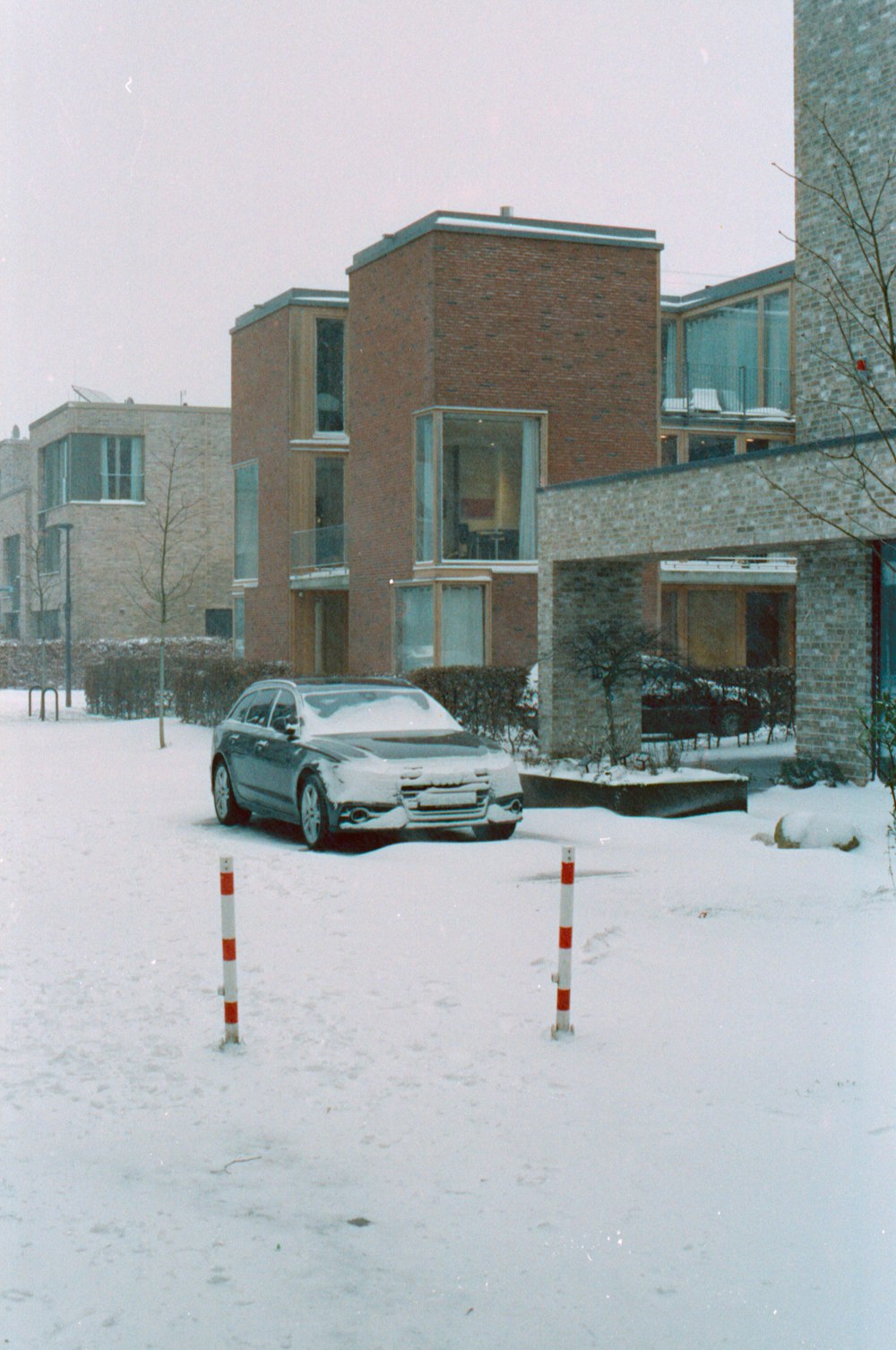 black car parked on snow covered road near brown concrete building during daytime