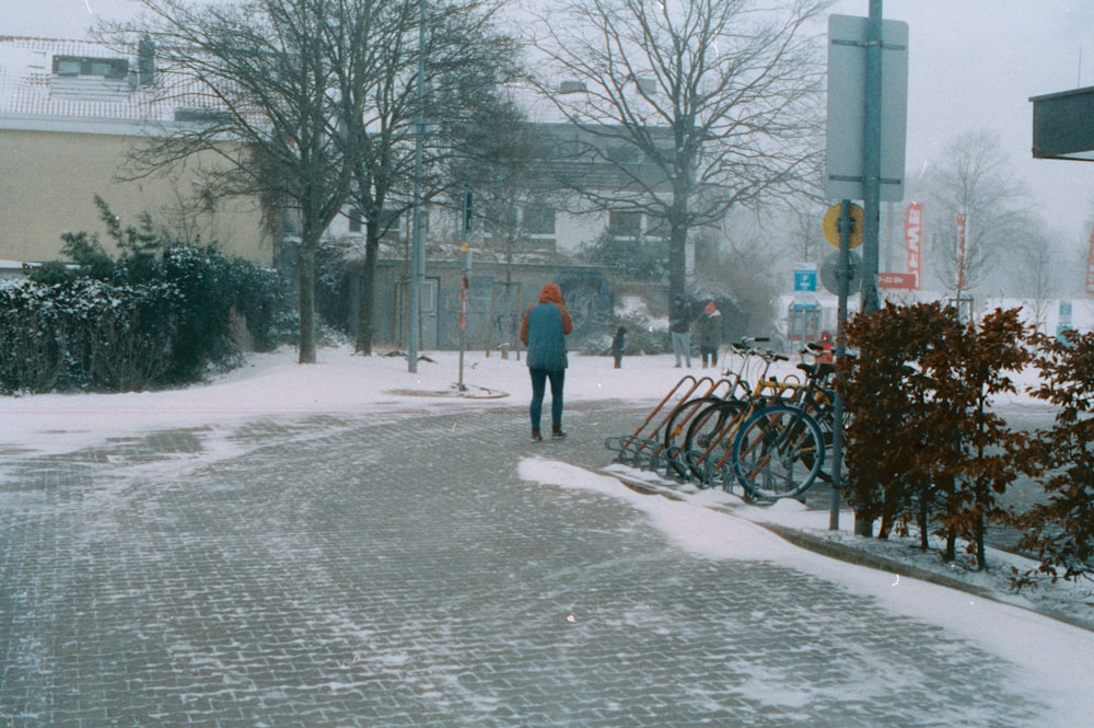 person in red jacket walking on snow covered road during daytime