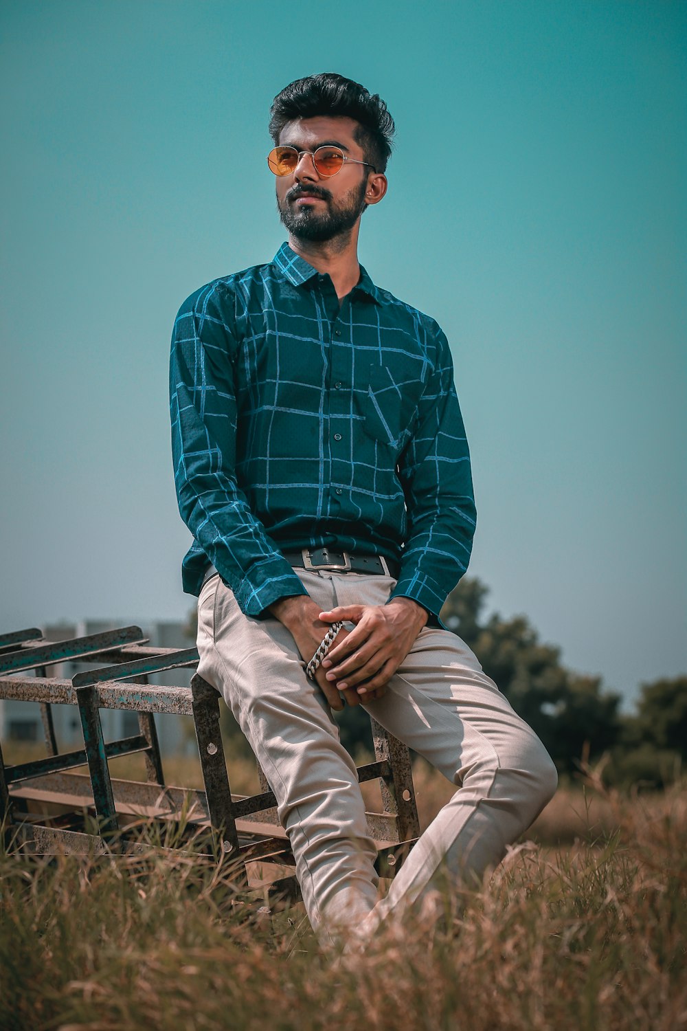 man in blue and black plaid dress shirt and brown pants sitting on brown wooden bench