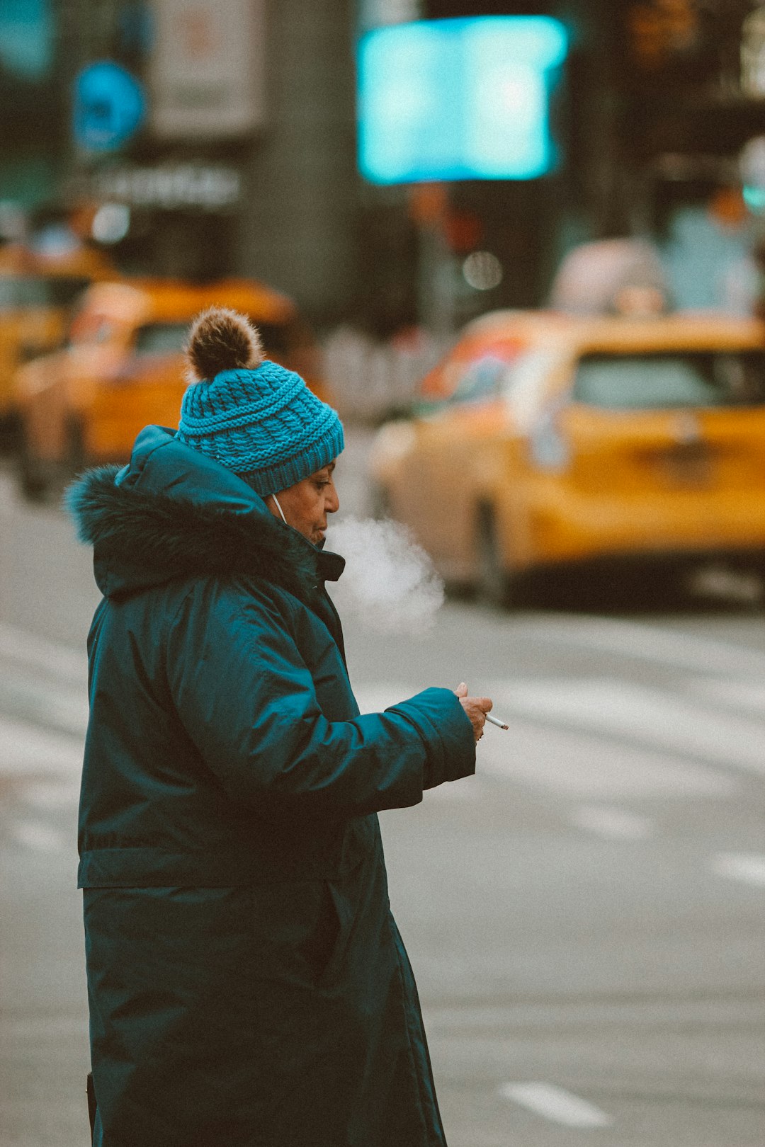 person in brown coat and brown knit cap holding white smartphone