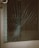 A glass door with a large spider web crack at the center, indicating significant impact. The crack radiates outward in a pattern typical of shattered glass. The metal door frame is visible on the left side.