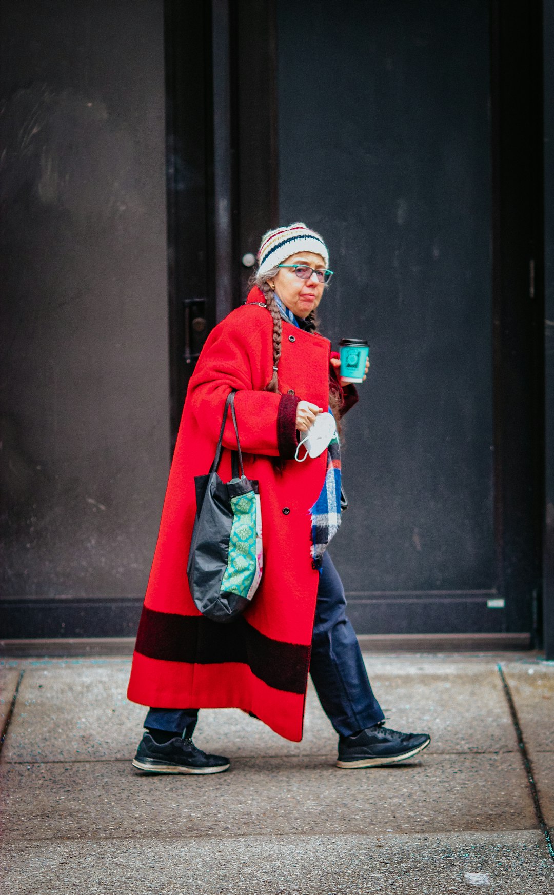 man in red coat standing near black wall