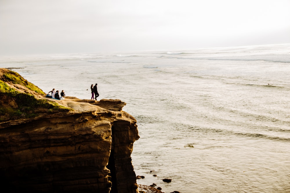 people standing on rock formation near sea during daytime