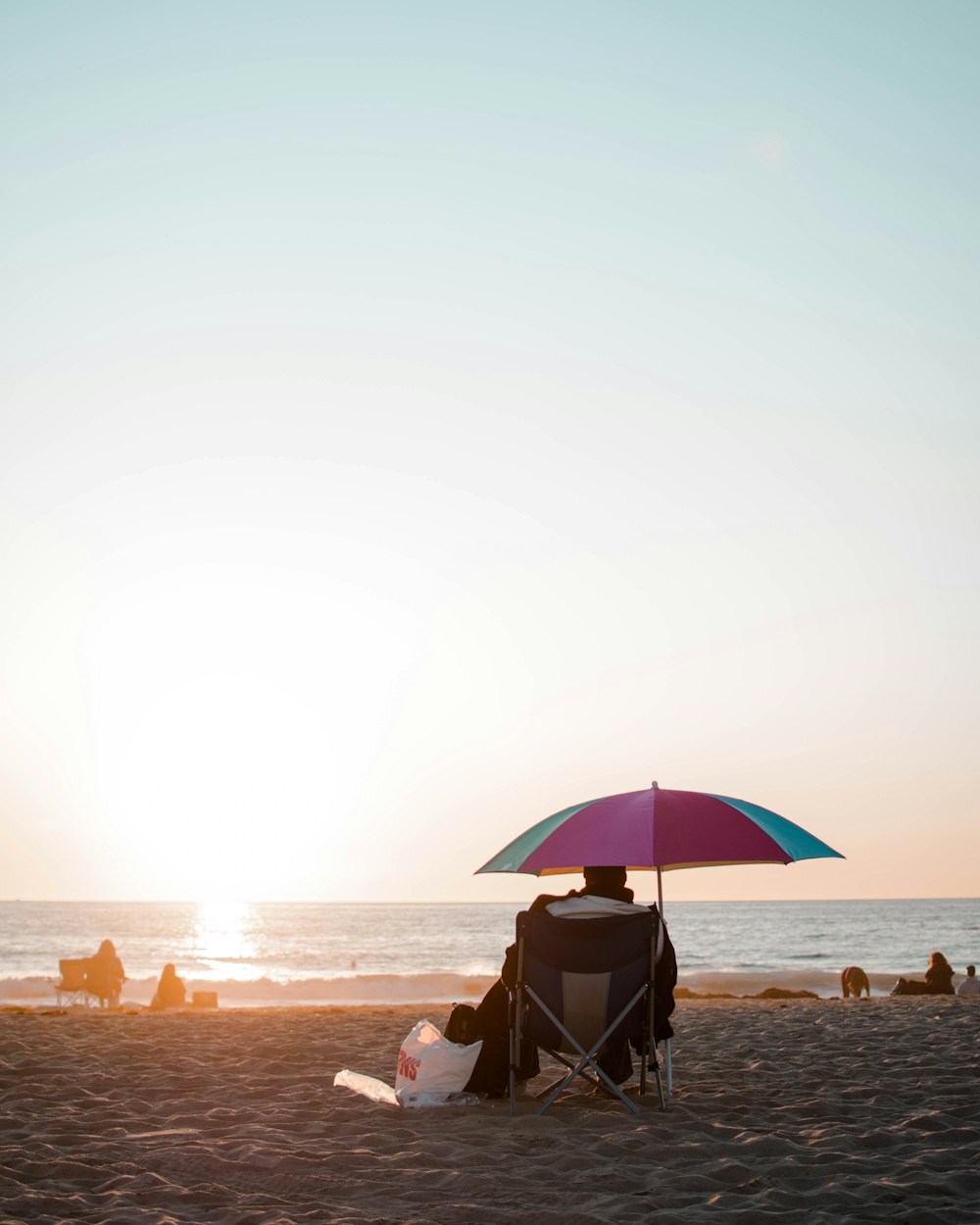 man and woman sitting on beach during sunset