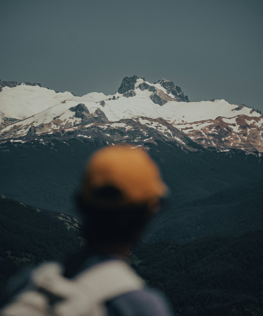 person in white shirt looking at snow covered mountains during daytime