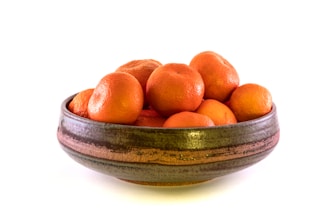 A rustic ceramic bowl filled with fresh fruit, highlighting the earthy texture and glaze.