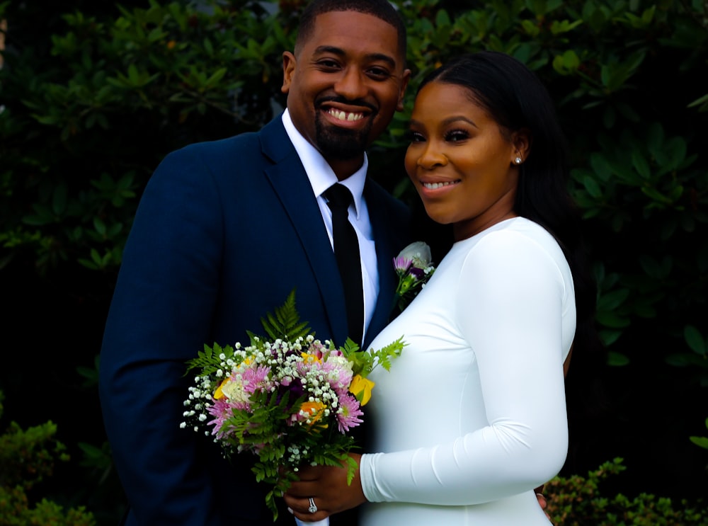 man in black suit jacket hugging woman in white dress