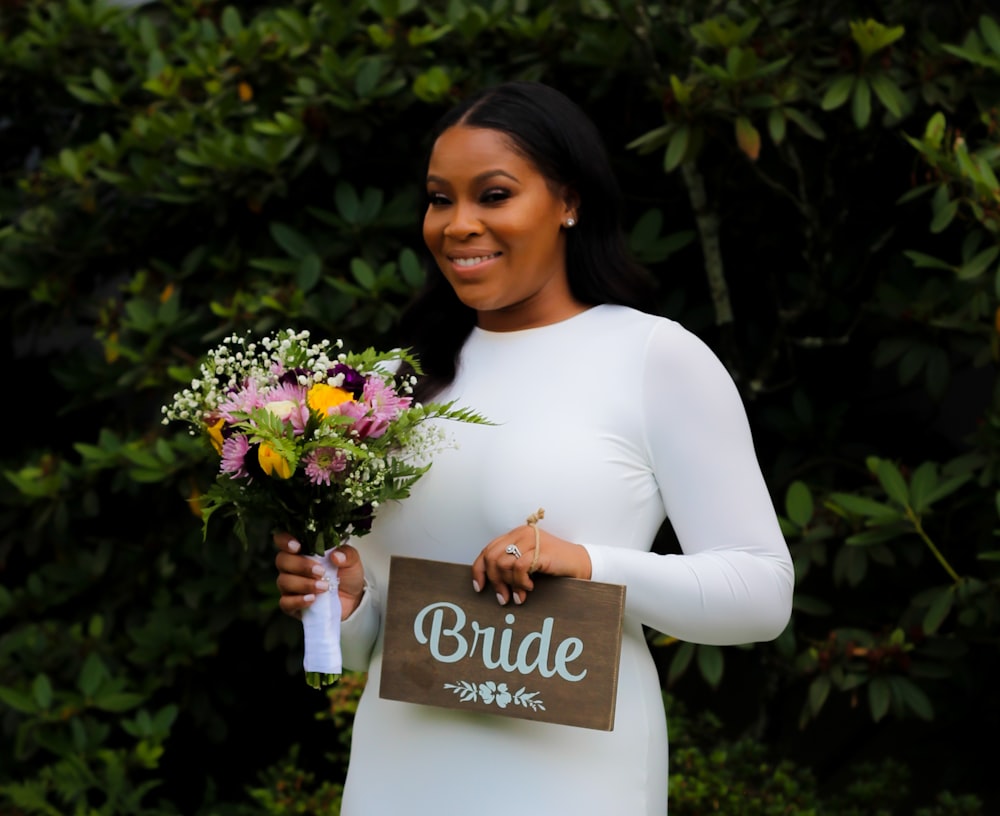 woman in white long sleeve shirt holding bouquet of flowers