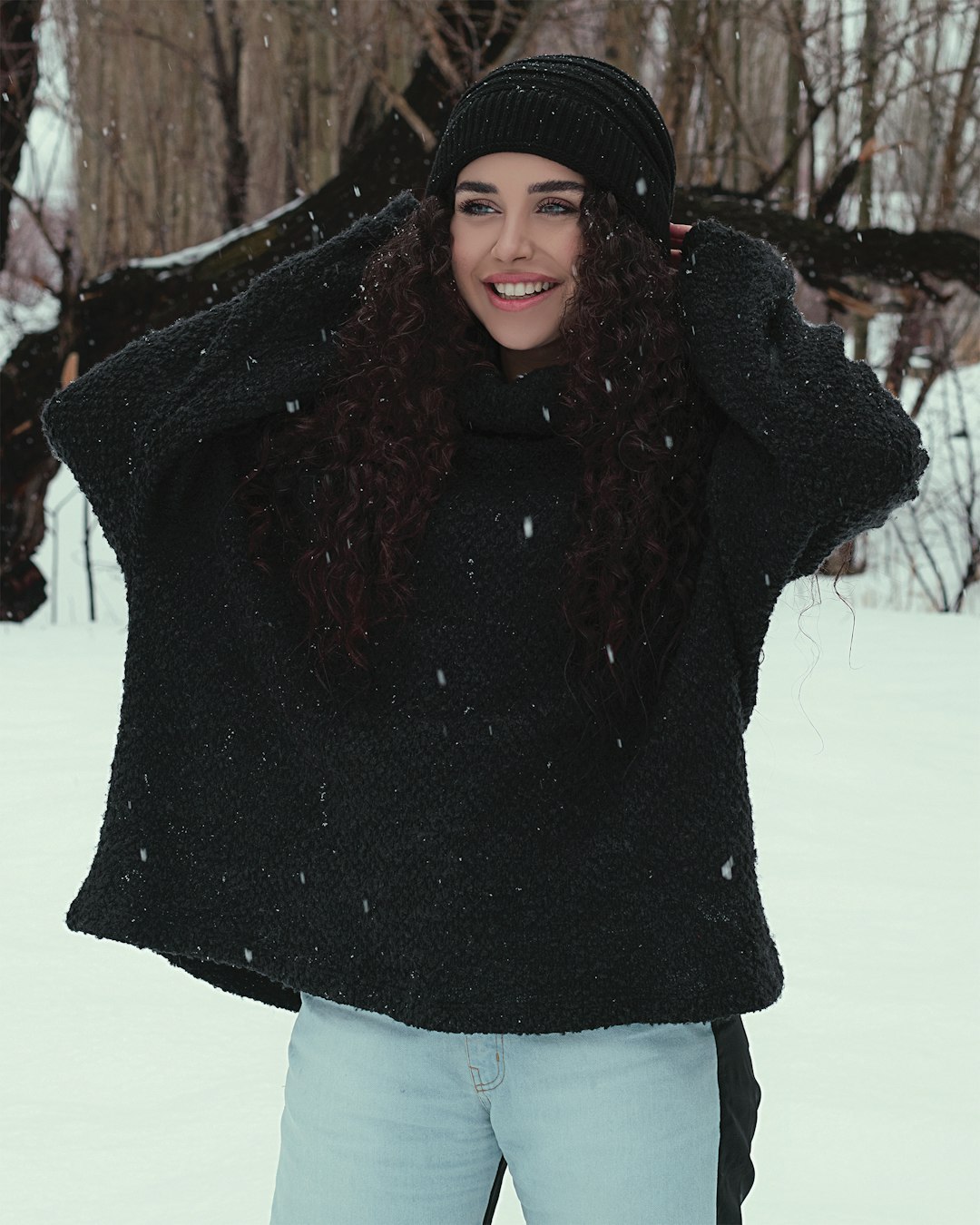 woman in black sweater and white skirt standing on snow covered ground during daytime