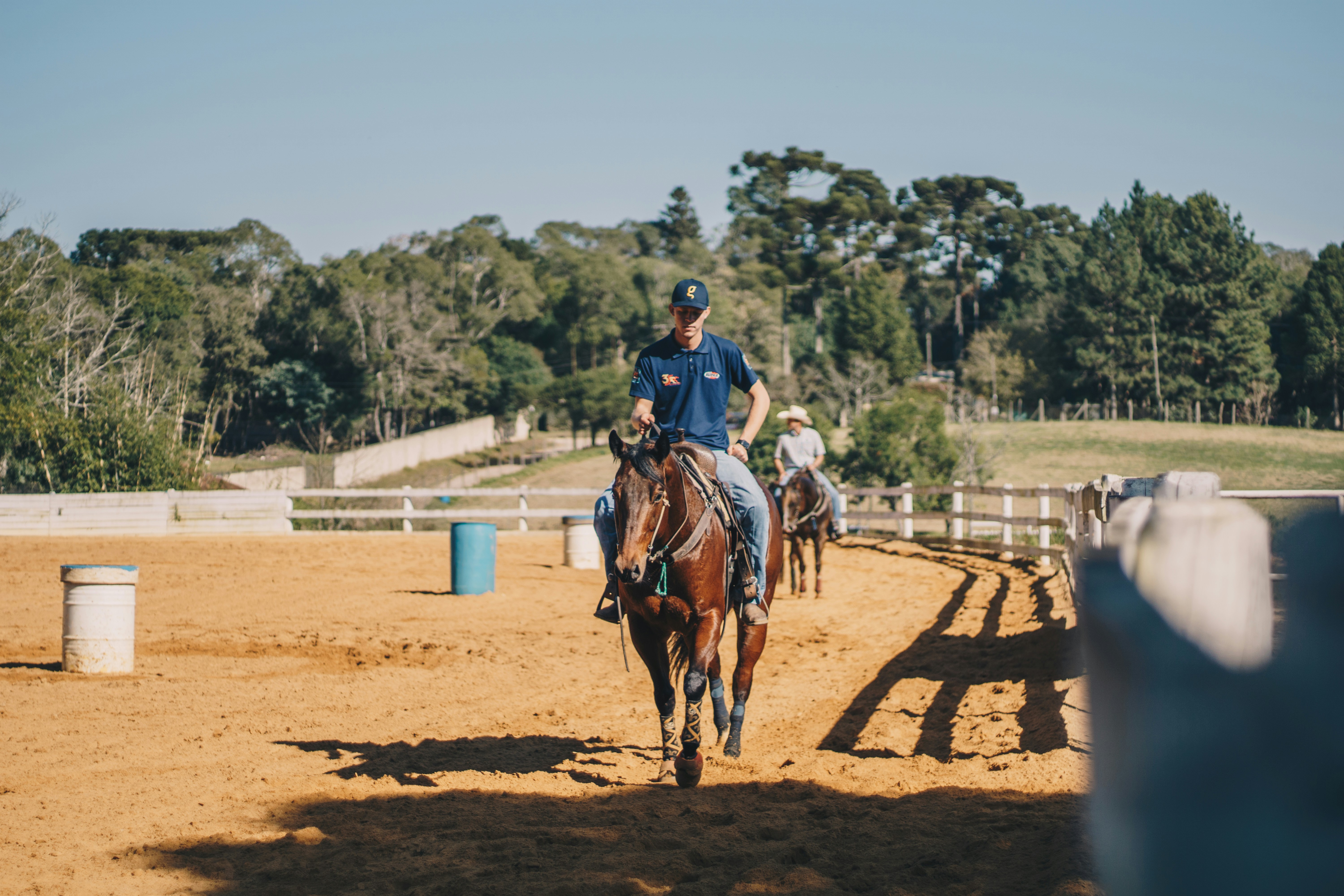 man in white shirt riding brown horse during daytime
