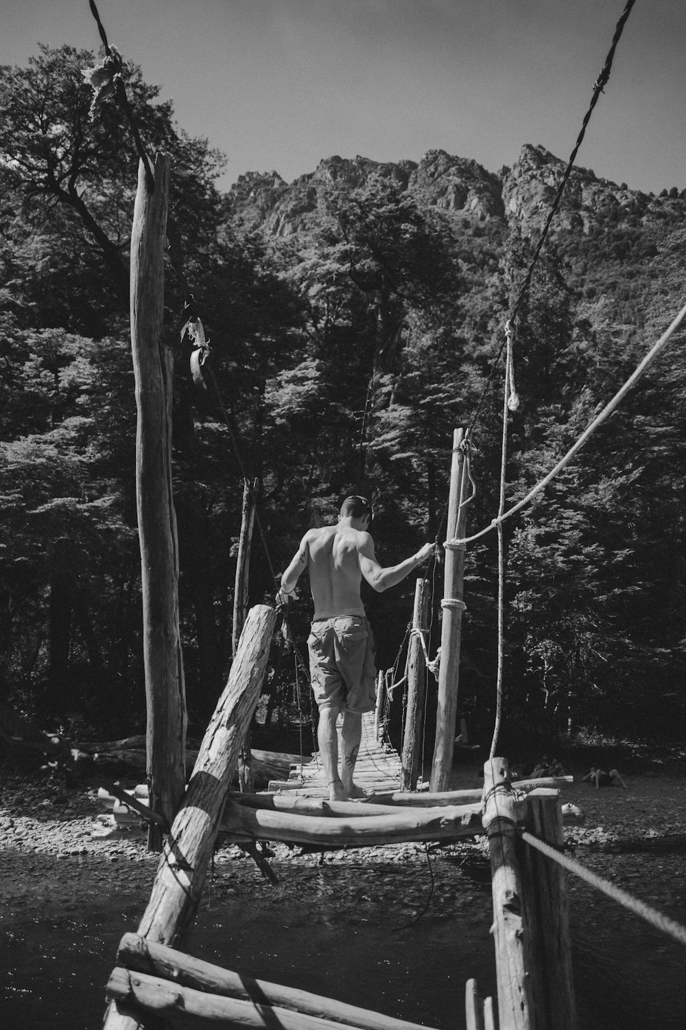 grayscale photo of man and woman standing on wooden bridge