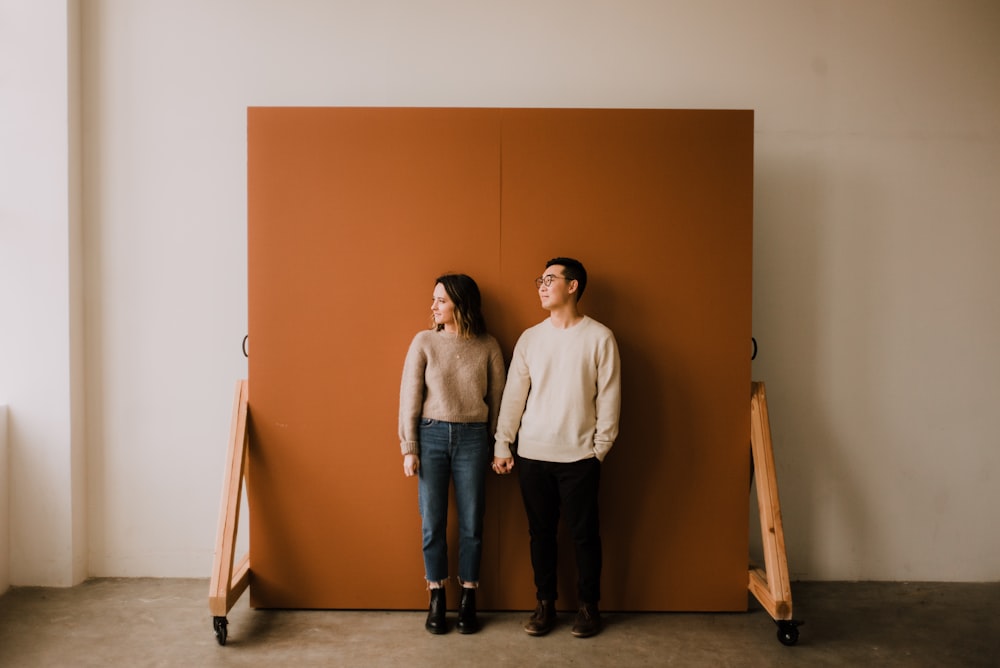 man and woman standing beside brown wall
