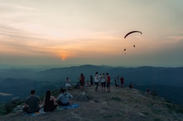 A group of diverse travelers enjoying a scenic view atop a mountain during sunset.