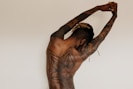 man with body tattoos raising his right arm