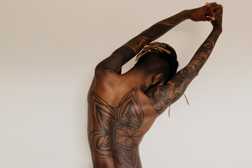 man with body tattoos raising his right arm