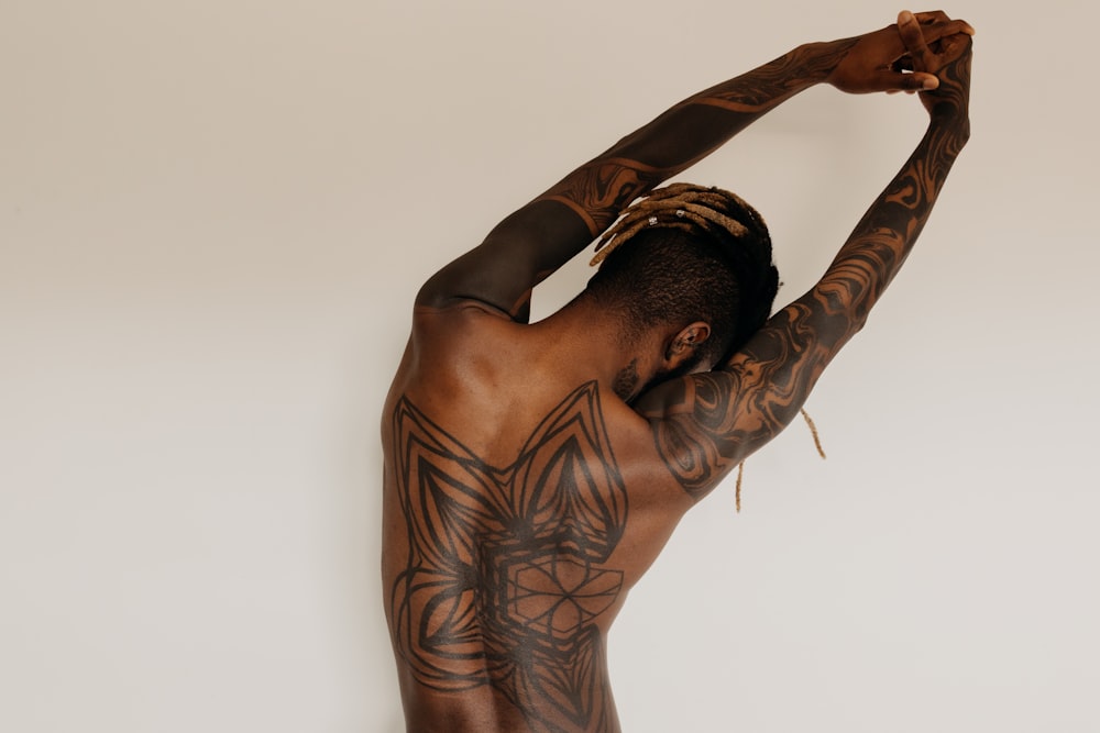 hombre con tatuajes en el cuerpo levantando su brazo derecho