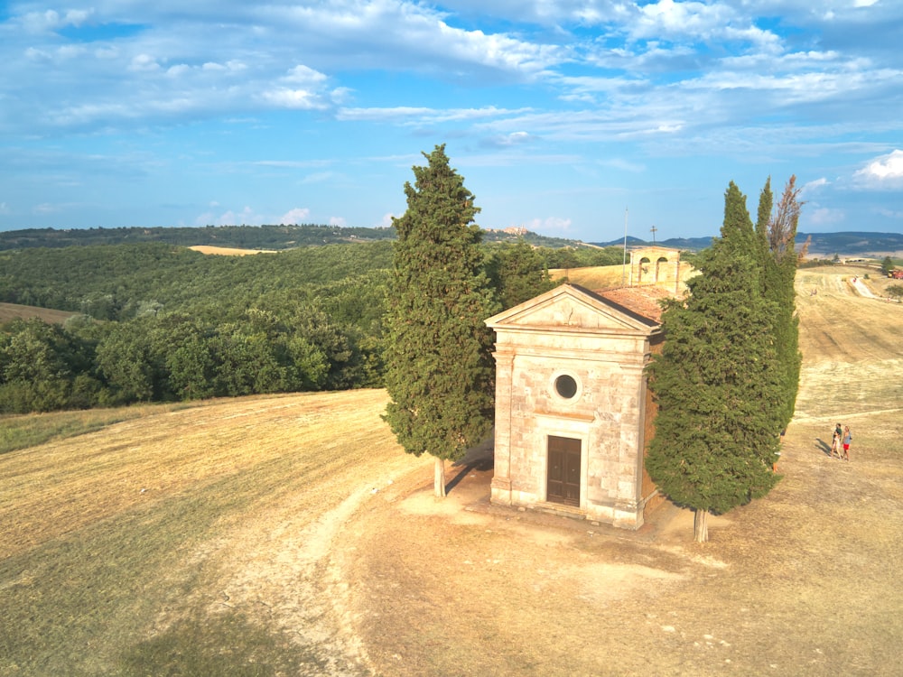 edificio in cemento bianco vicino agli alberi verdi sotto il cielo blu durante il giorno