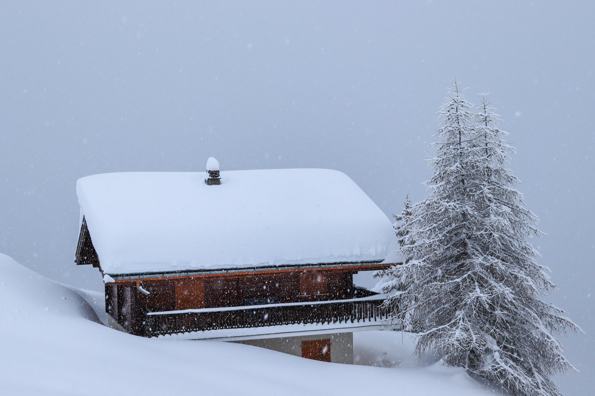 A snow-covered house in daytime, a reminder that the owner keeps the roof, ice dams, and structural hazards no matter who shovels the walk.