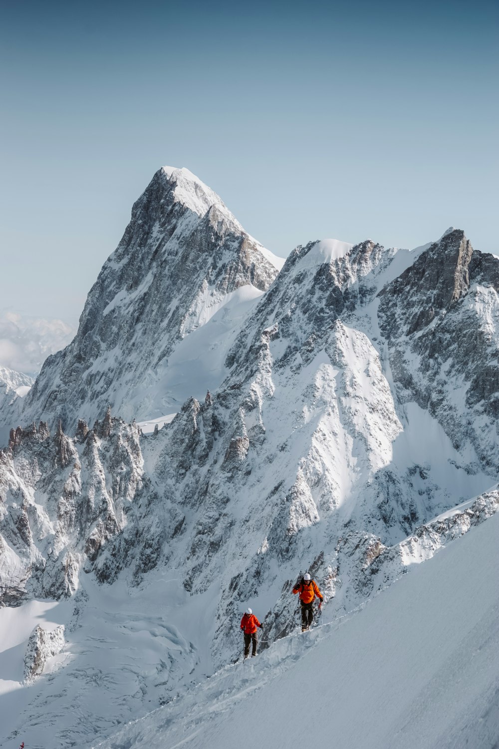 Persona in giacca rossa e pantaloni neri in piedi sulla montagna coperta di neve durante il giorno