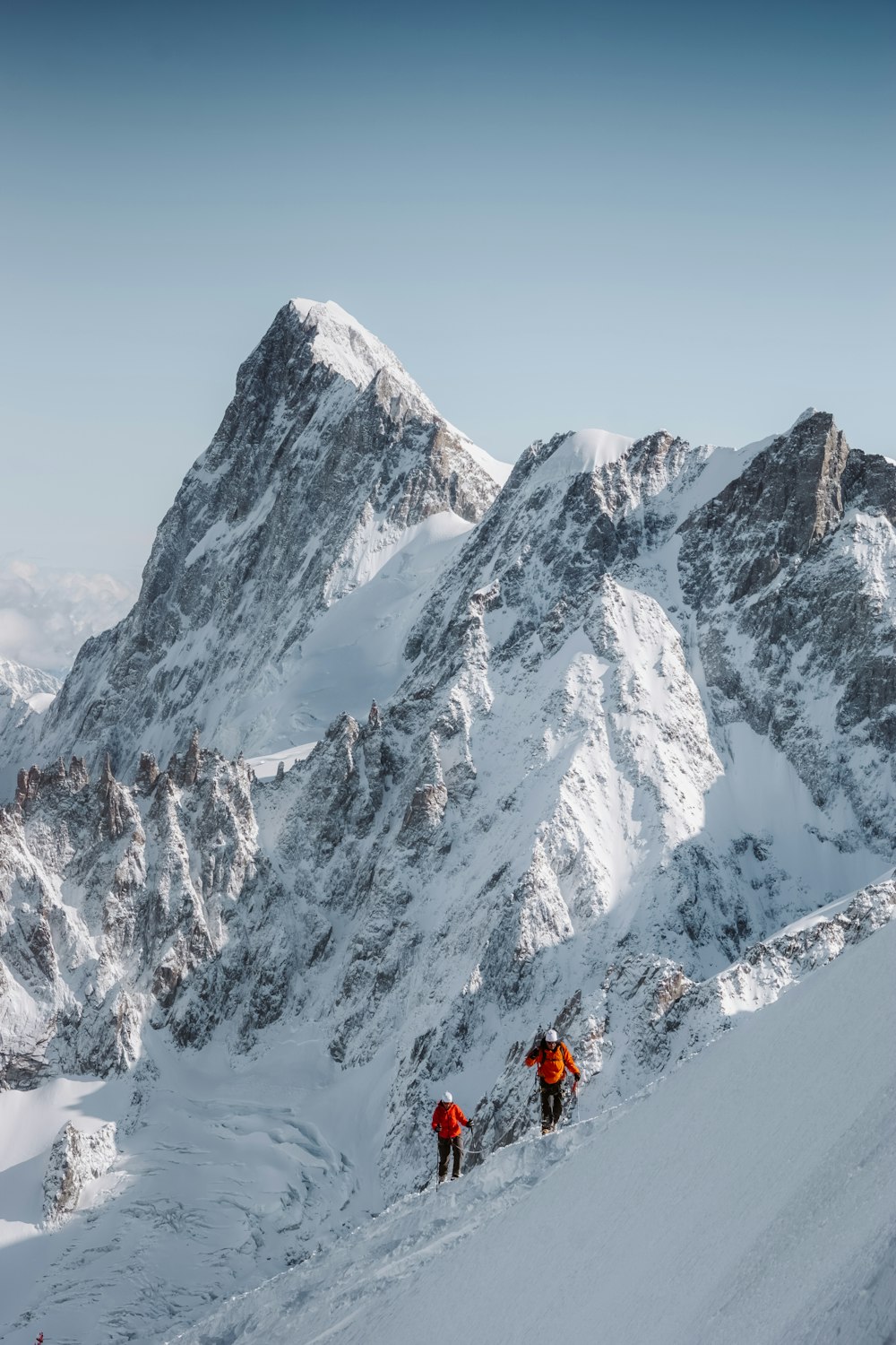 pessoa em jaqueta vermelha e calças pretas em pé na montanha coberta de neve durante o dia