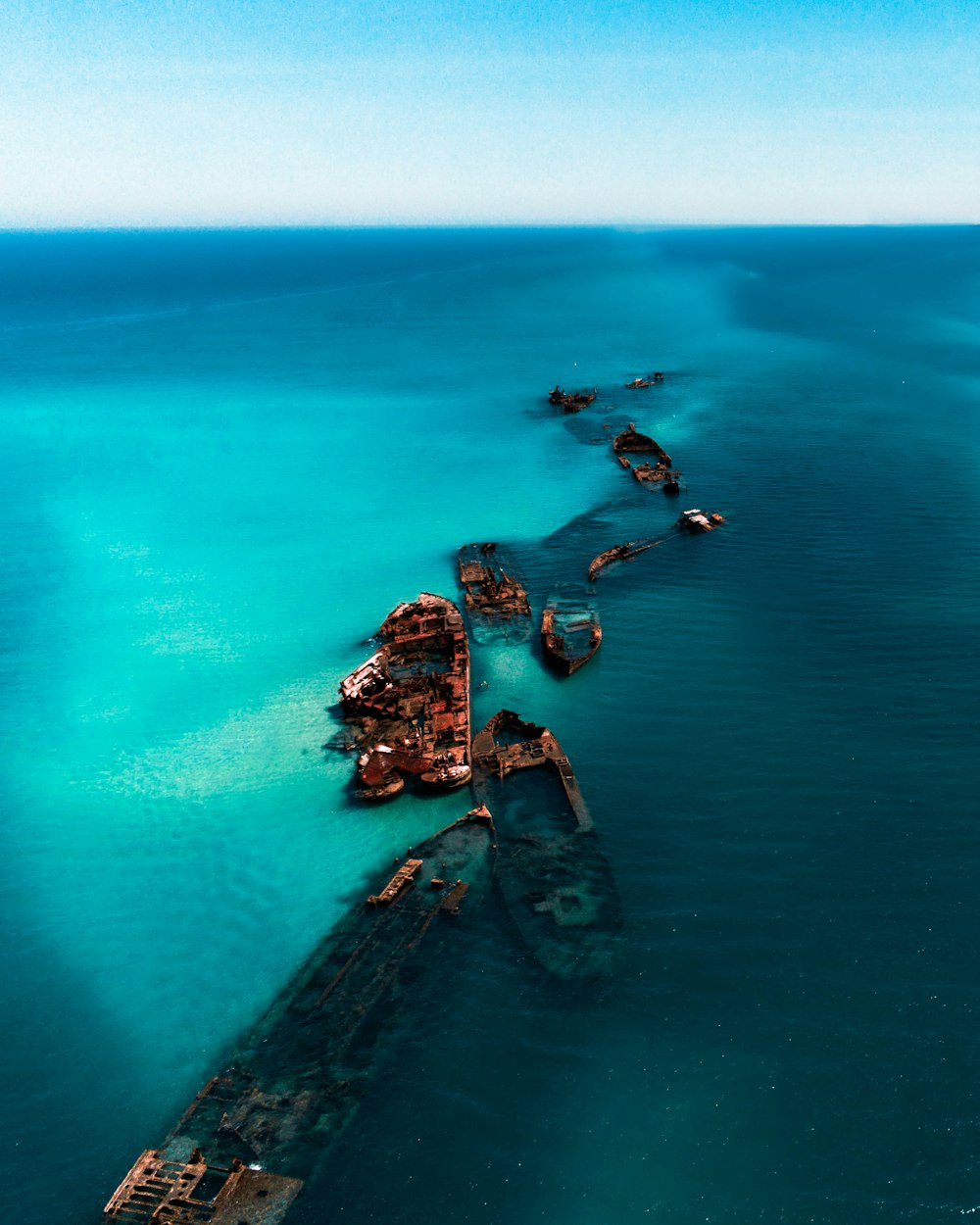 formação rochosa marrom e preta no mar azul durante o dia