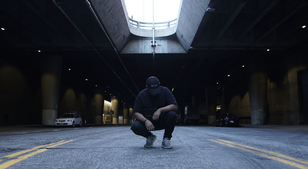 man in black hoodie sitting on white concrete bench