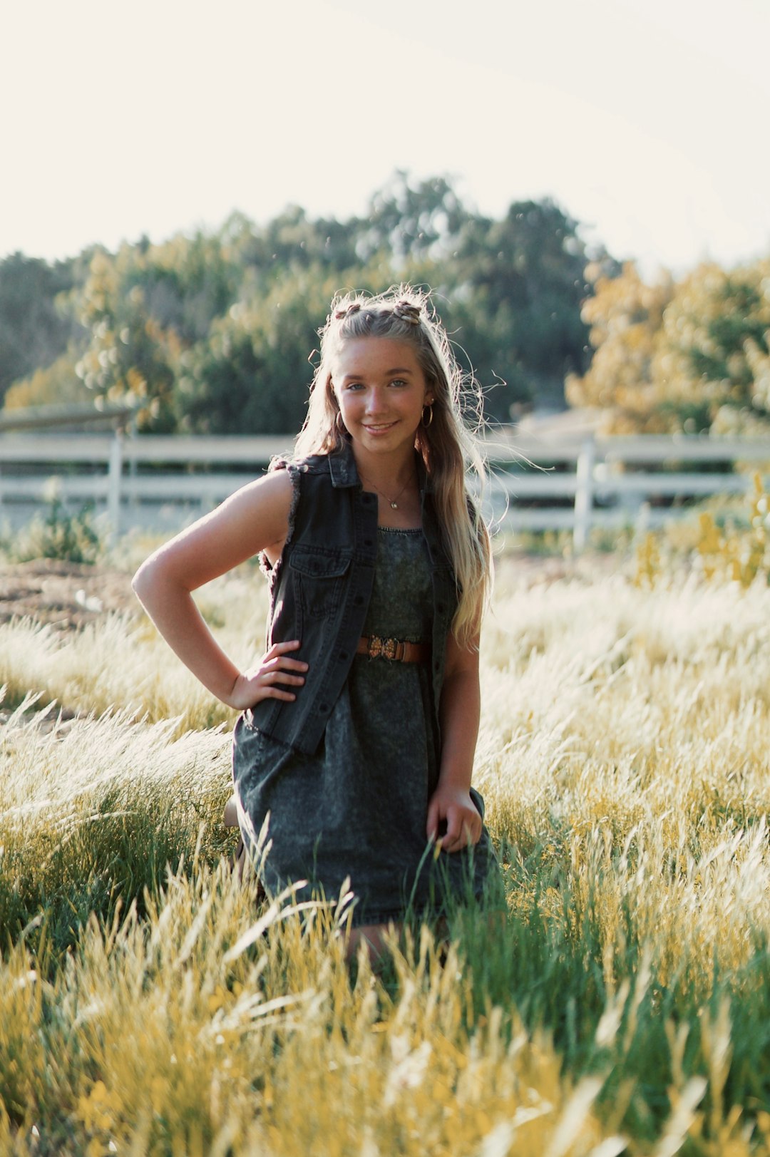 woman in blue denim dungaree standing on green grass field during daytime