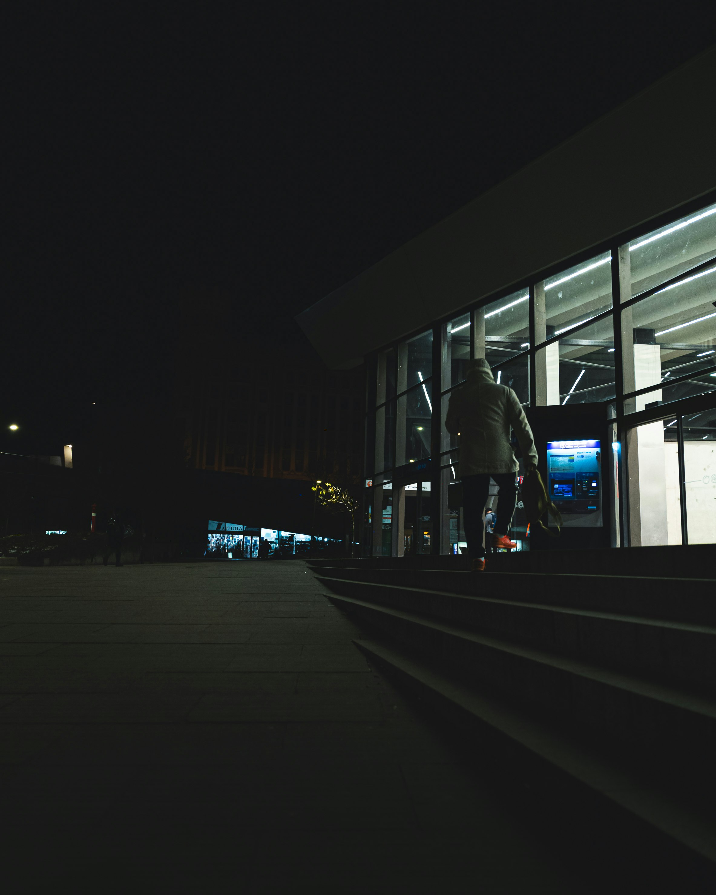 man in black jacket walking on sidewalk during night time
