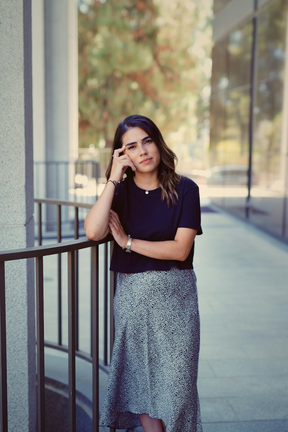 woman in black crew neck t-shirt and gray and white floral skirt standing on gray