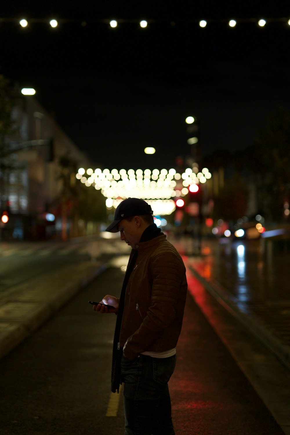man in brown coat standing on sidewalk during night time