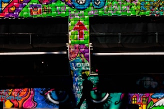 A candid street portrait of a person walking past colorful graffiti walls.