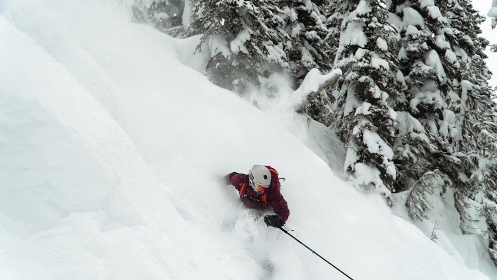 a person skiing down a snowy mountain with trees in the background