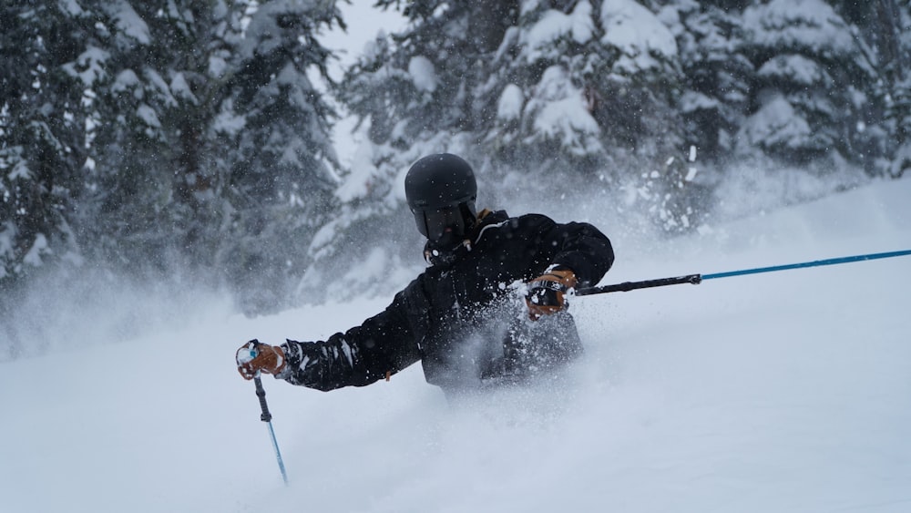 man in black jacket and black pants riding ski blades on snow covered ground during daytime