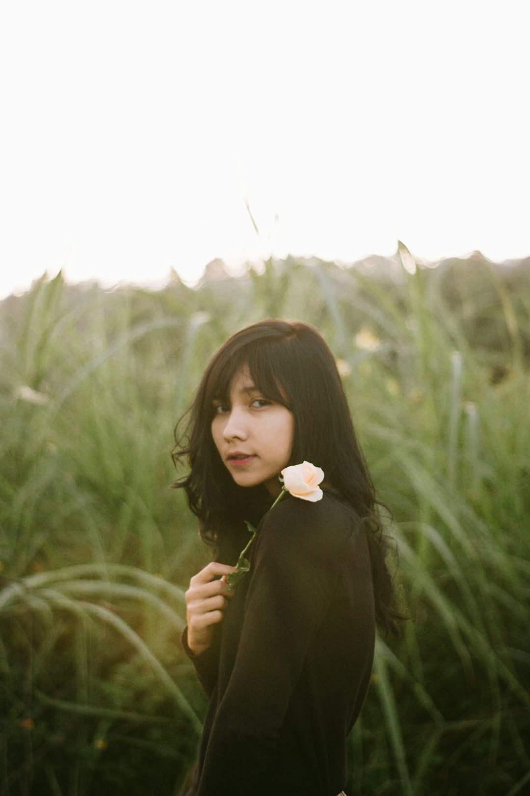 woman in black long sleeve shirt holding white flower