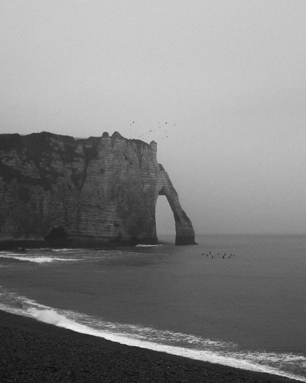 grayscale photo of rock formation on sea