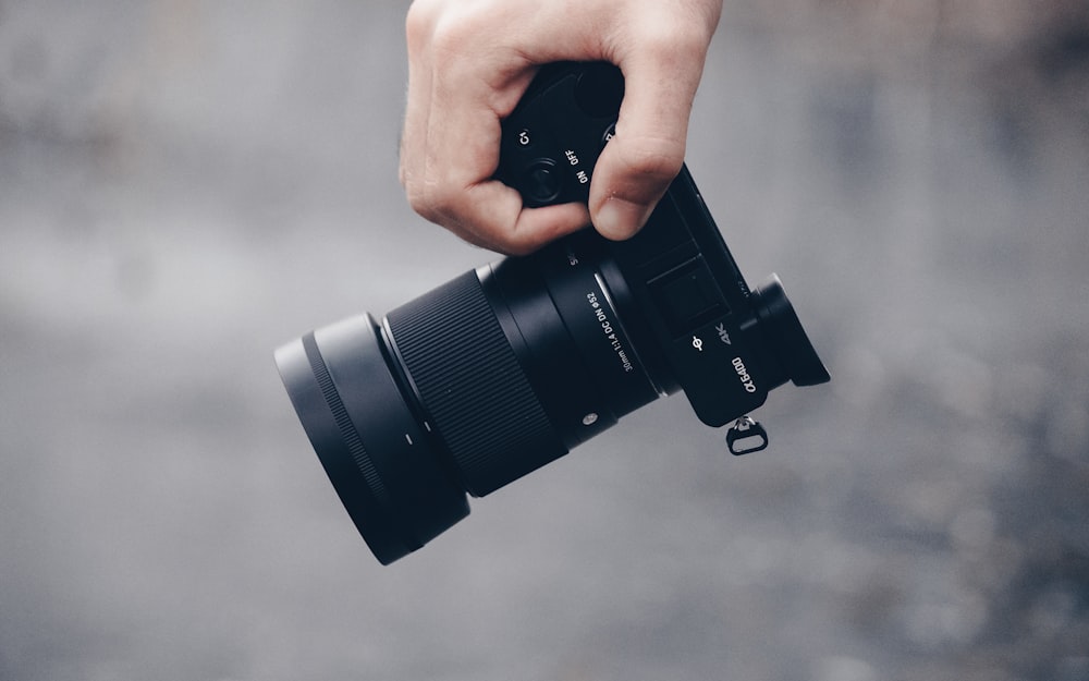 person holding black dslr camera lens