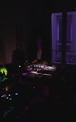 A moody, dark-themed DJ studio with turntables and sound equipment glowing under soft blue lights.