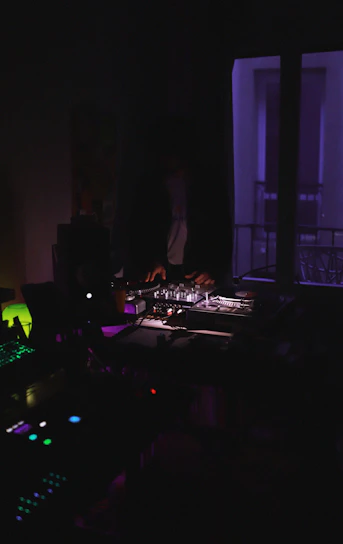 Dimly lit DJ studio with glowing electric blue and deep violet lights surrounding high-end mixing equipment.