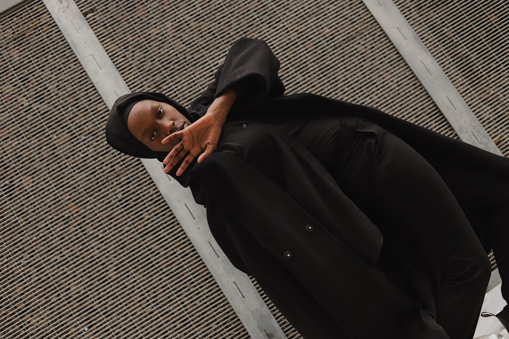 man in black thobe lying on white bench