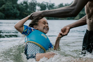girl in blue and yellow tank top playing on water during daytime