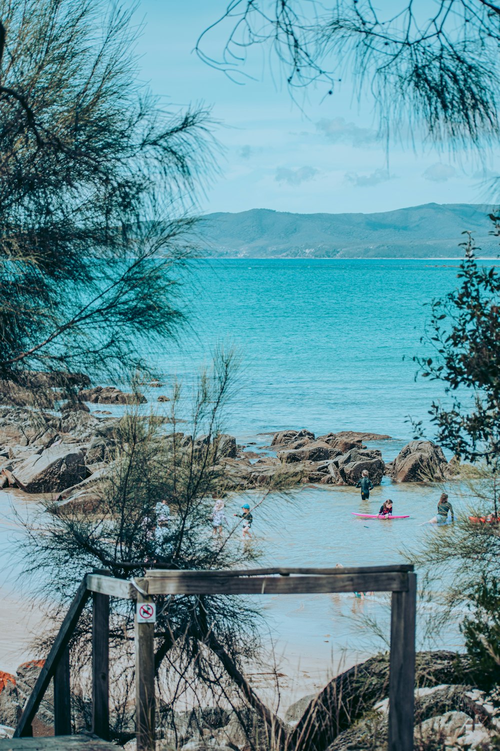 people sitting on brown wooden bench near body of water during daytime