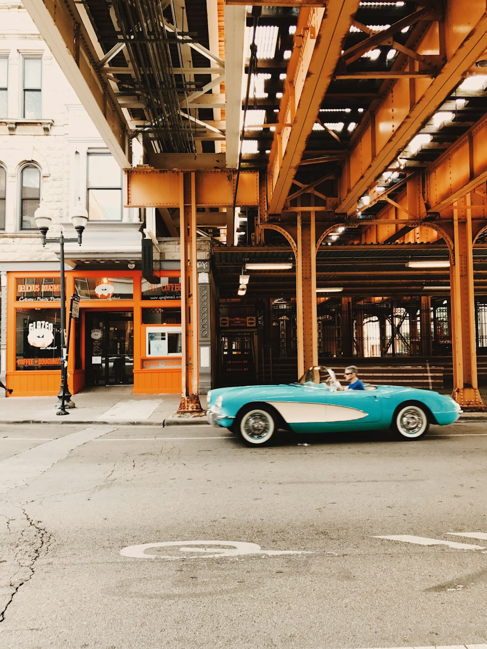teal coupe parked beside brown wooden building during daytime