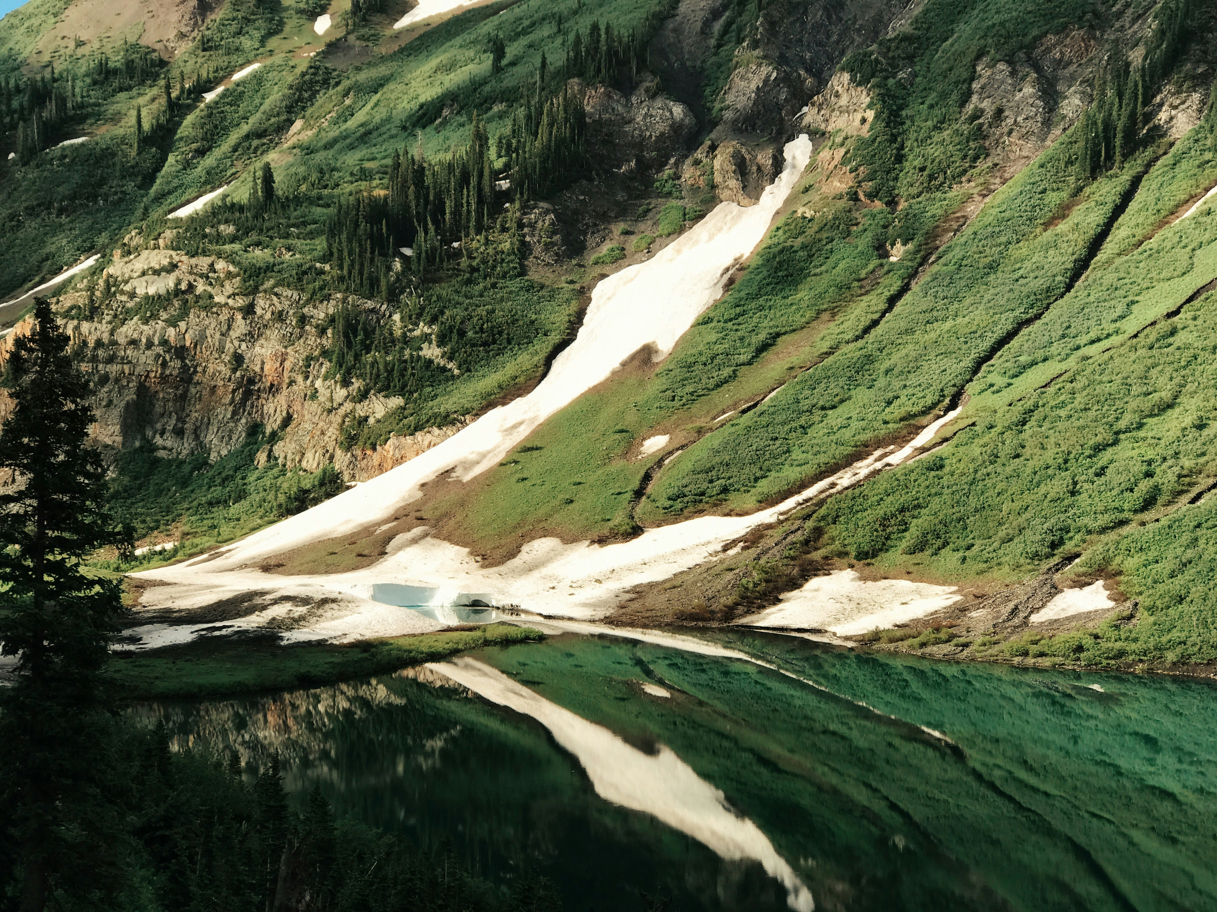 green and brown mountains during daytime emerald green teams background
