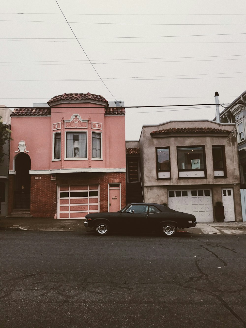 black coupe parked beside red concrete building during daytime
