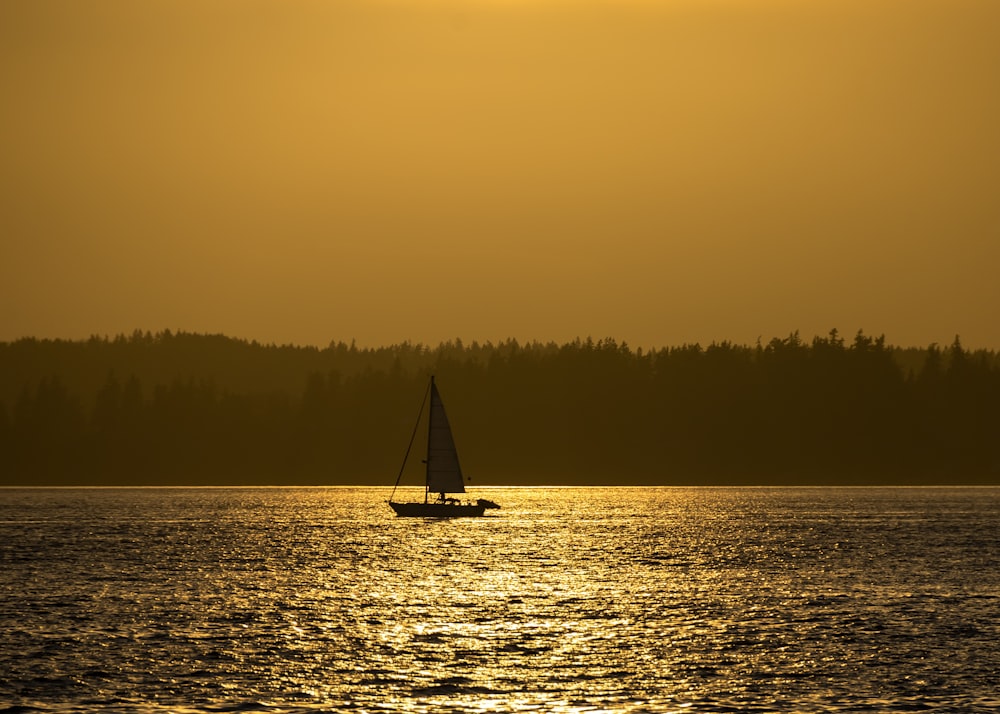 silhouette of sailboat on sea during sunset