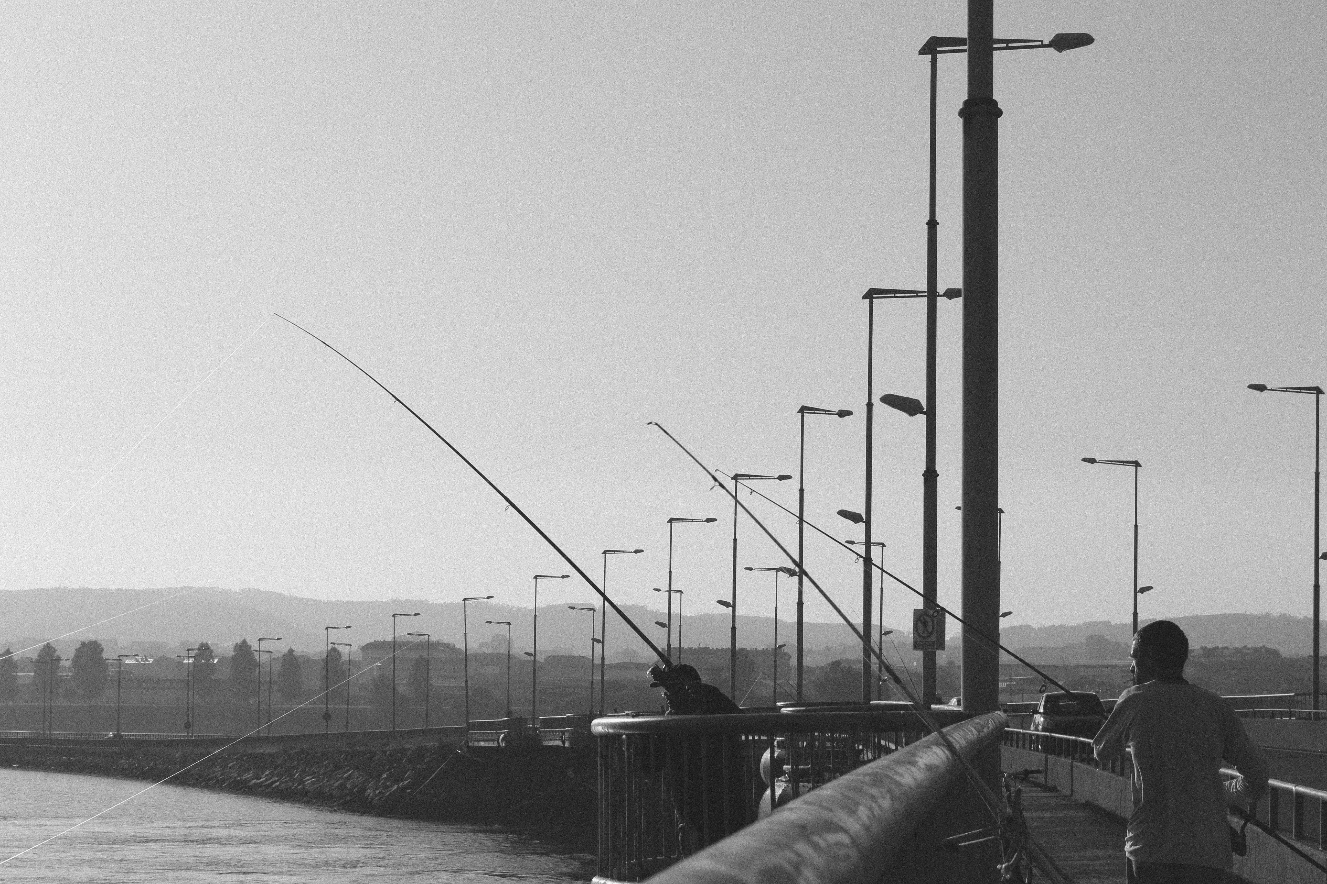 grayscale photo of person walking on bridge