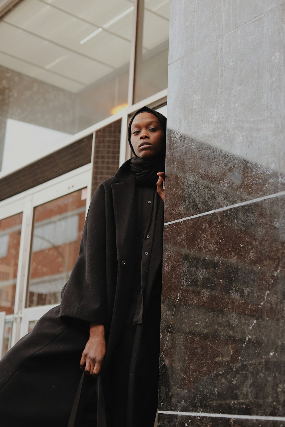 black coat standing beside glass window